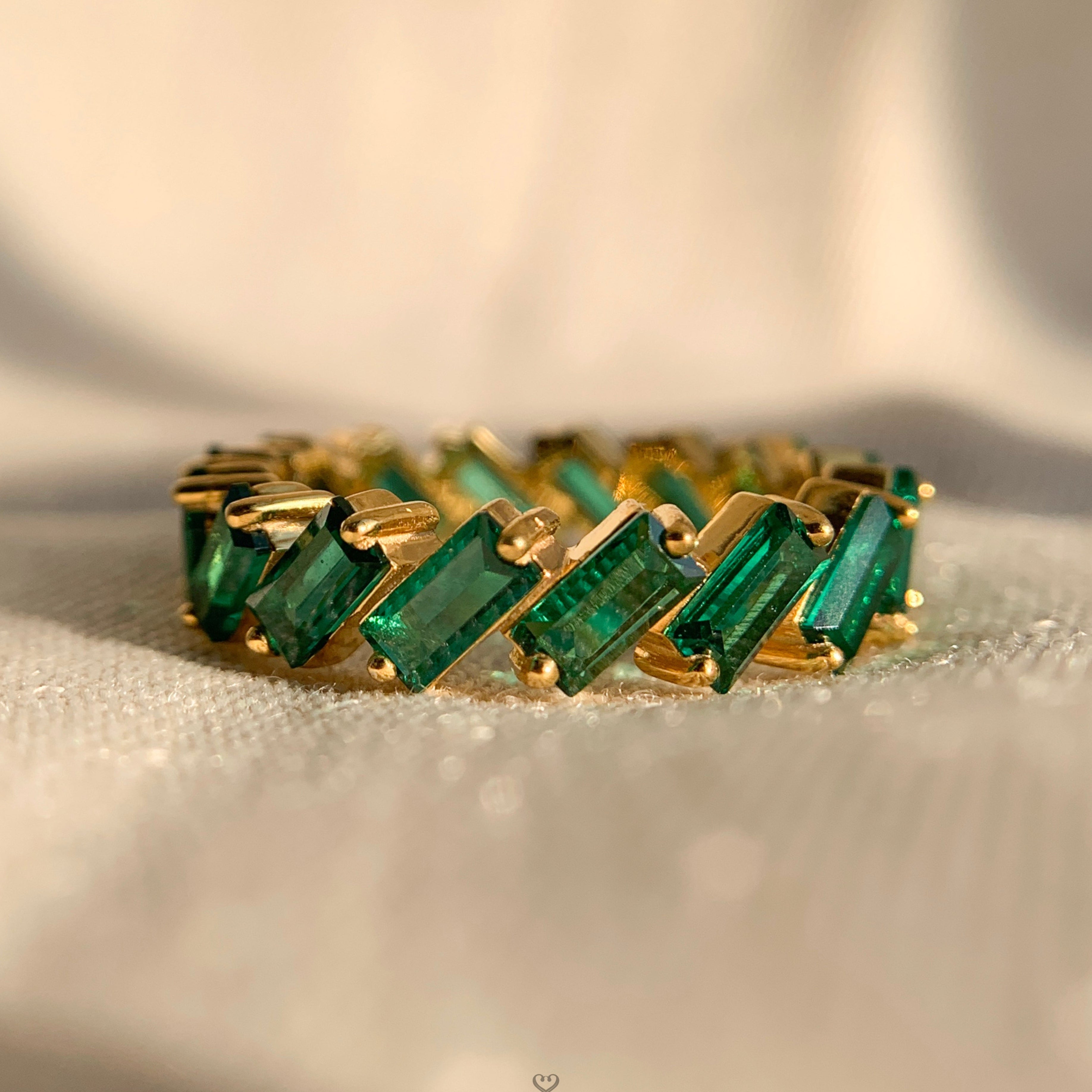 Baguette cut emerald infinity wedding band in sleek white gold setting